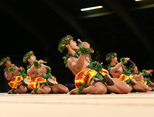A men’s hula group performing in competition at the Merrie Monarch Festival in Hilo, Hawaii—showcasing traditional mele, hula kahiko, and Hawaiian regalia.