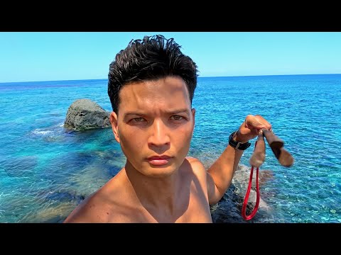 Hawaii HammaHS holding a 3-prong spear by the ocean in Hawaii
